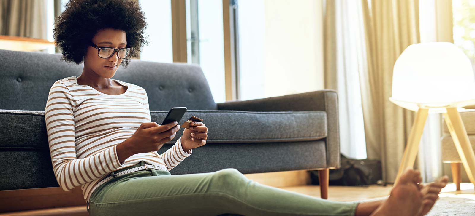 Young person sitting on the floor shopping on their phone.